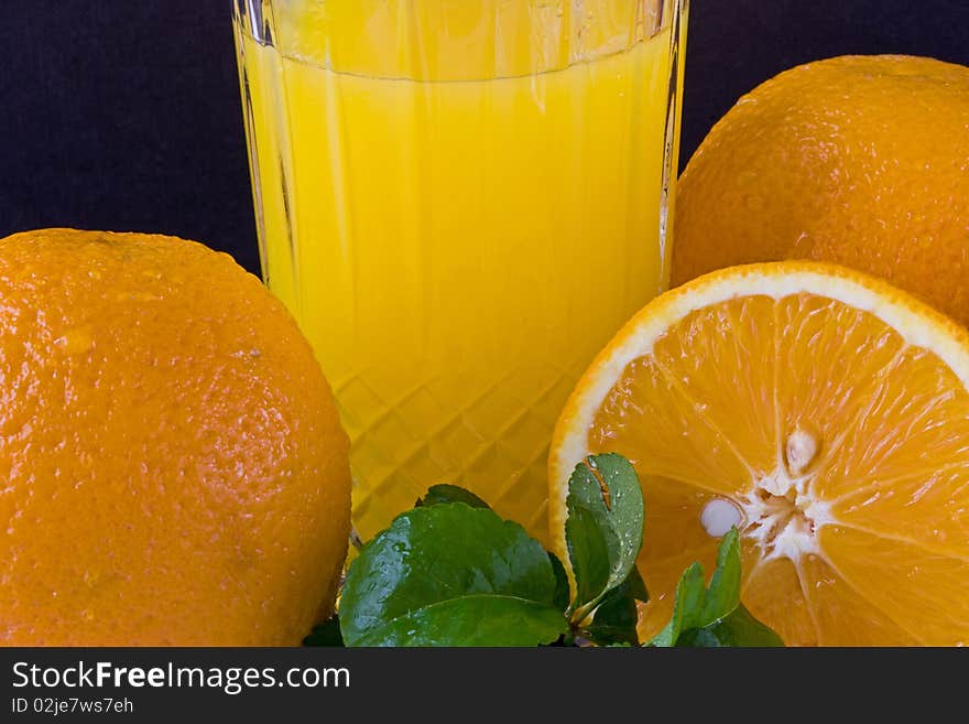 A group of oranges with leaf and a glass of juice. A group of oranges with leaf and a glass of juice