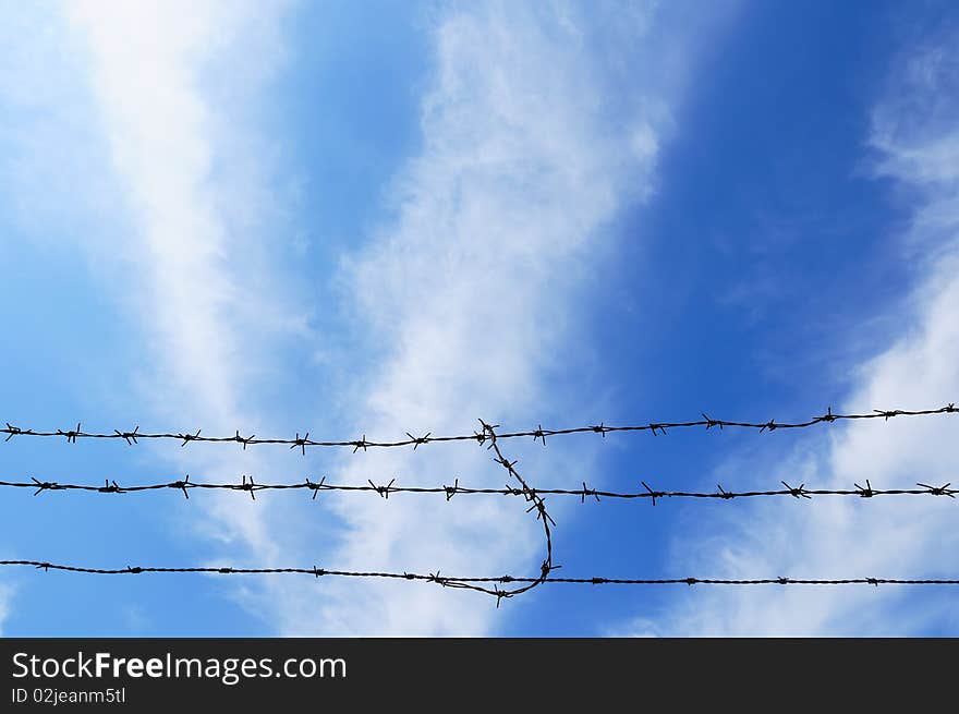 Barbed wire on the blue sky background