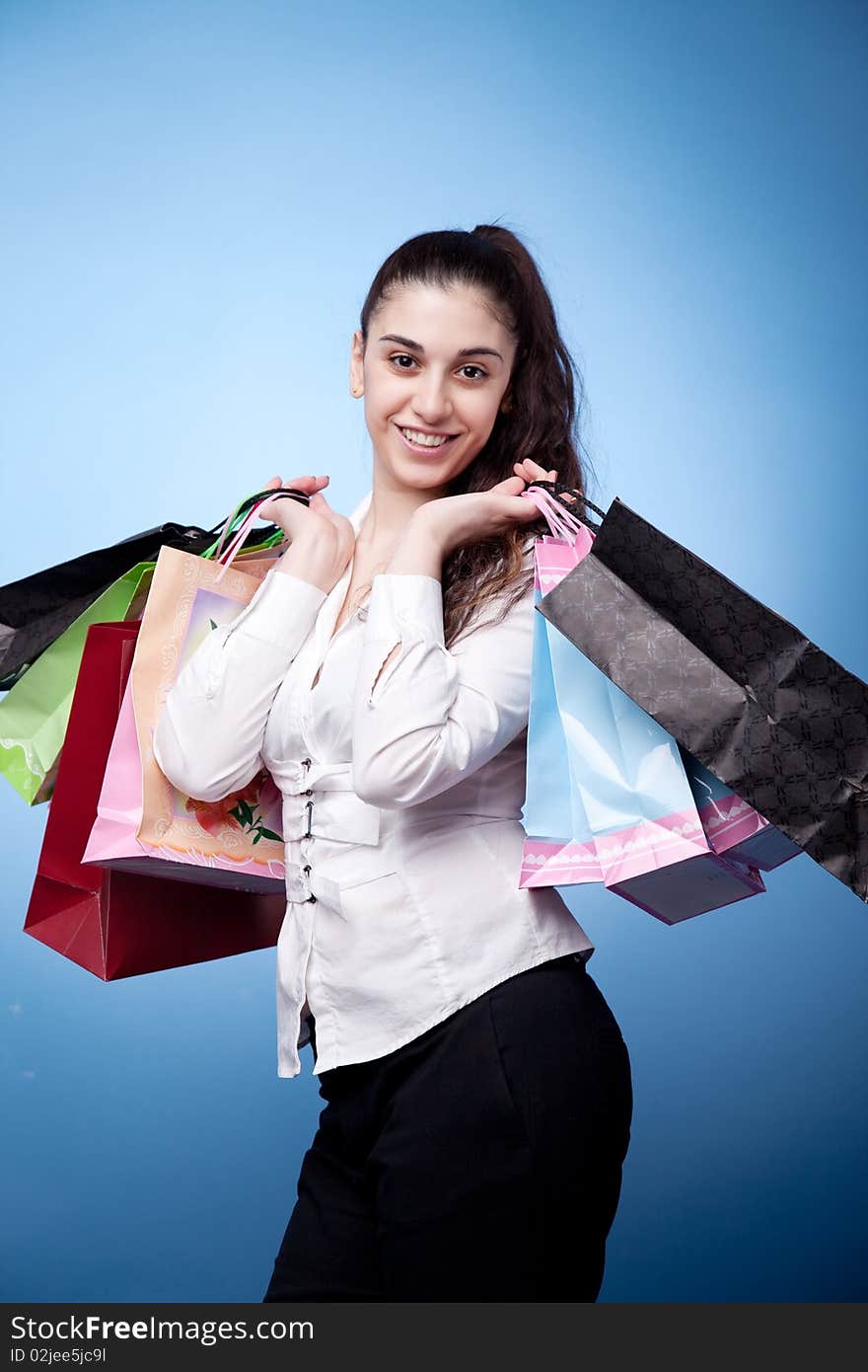 Attractive woman with shopping bags on blue background