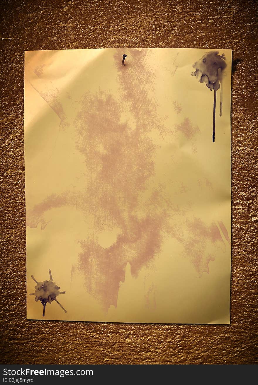 The paper with stains and blots hangs on an old wall. Vintage background.