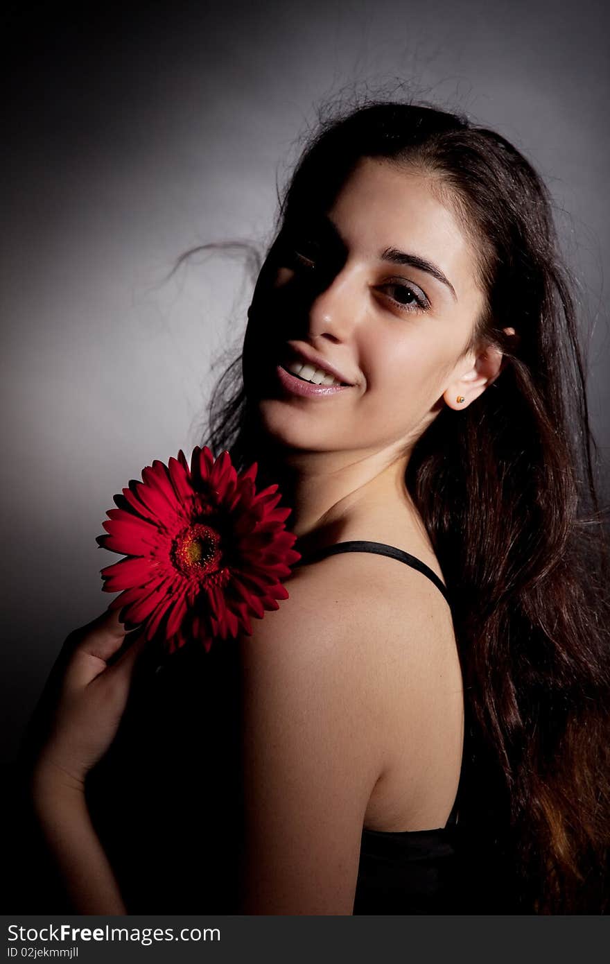 Attractive woman with red flower on black background