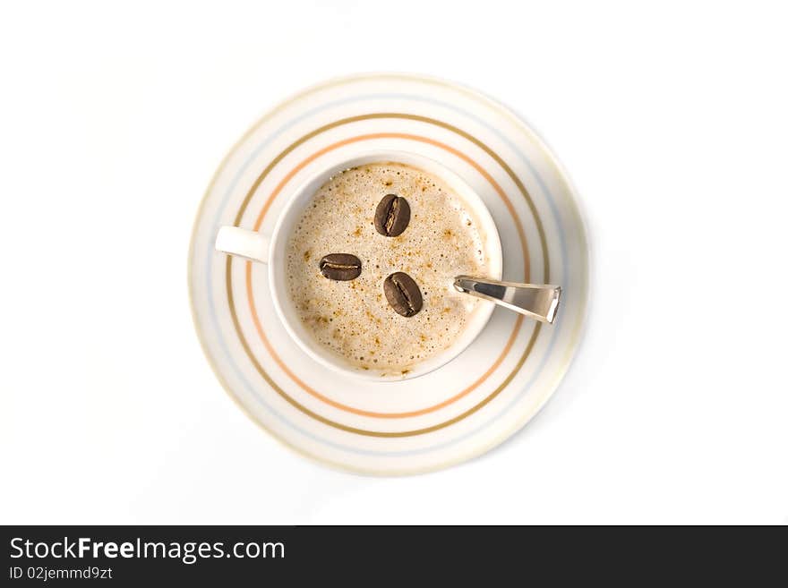 Top view of a coffee cup filled with capuccino and coffee beans