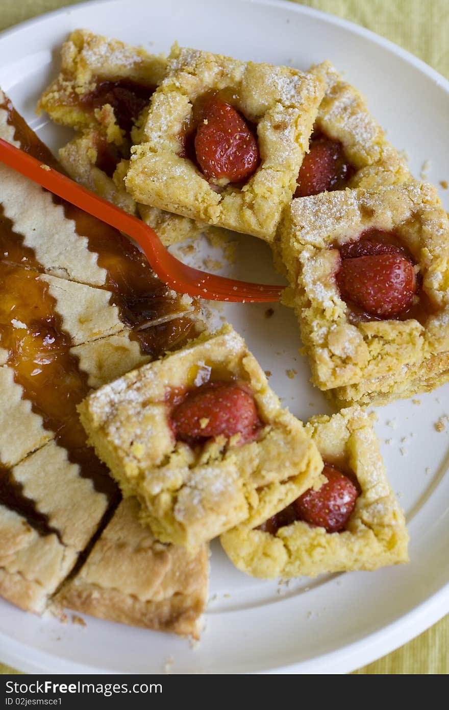 Pieces of  strawberry pie on a plate and a  red plastic fork. Pieces of  strawberry pie on a plate and a  red plastic fork