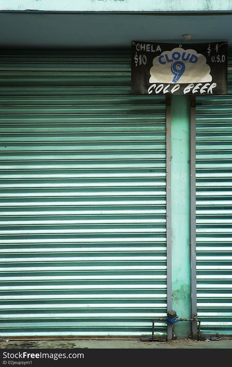 A beer sign in front of a green shuttered building along the Pacific Coast of Mexico. A beer sign in front of a green shuttered building along the Pacific Coast of Mexico.