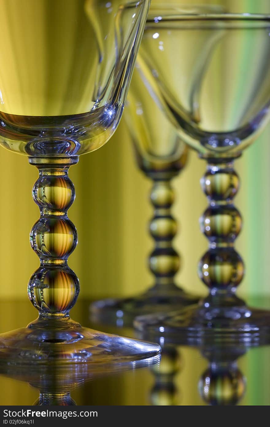 Three wine glasses on yellow background with detailed focus on front glass. Three wine glasses on yellow background with detailed focus on front glass