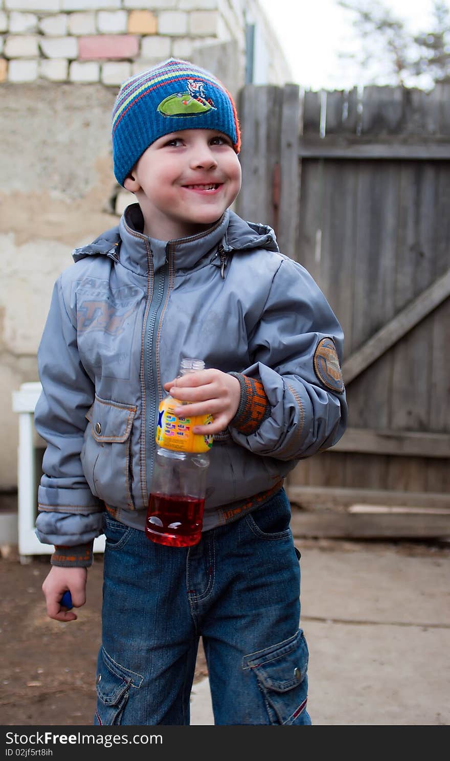 The wriggling boy holding in a hand a bottle with juice