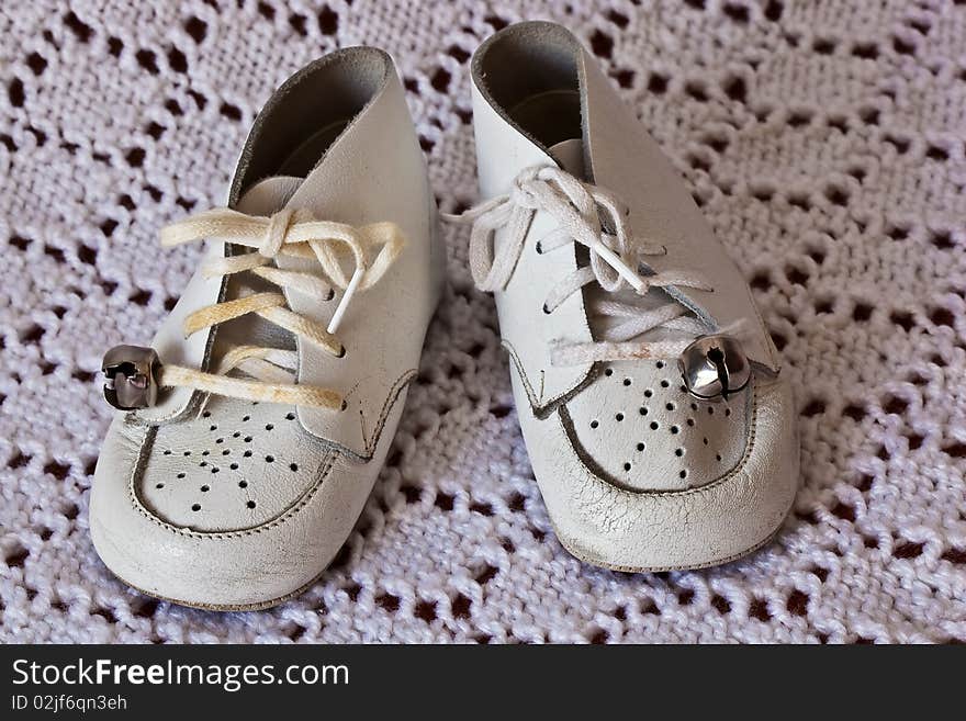 Soft white leather baby shoes on a white crochet baby blanket