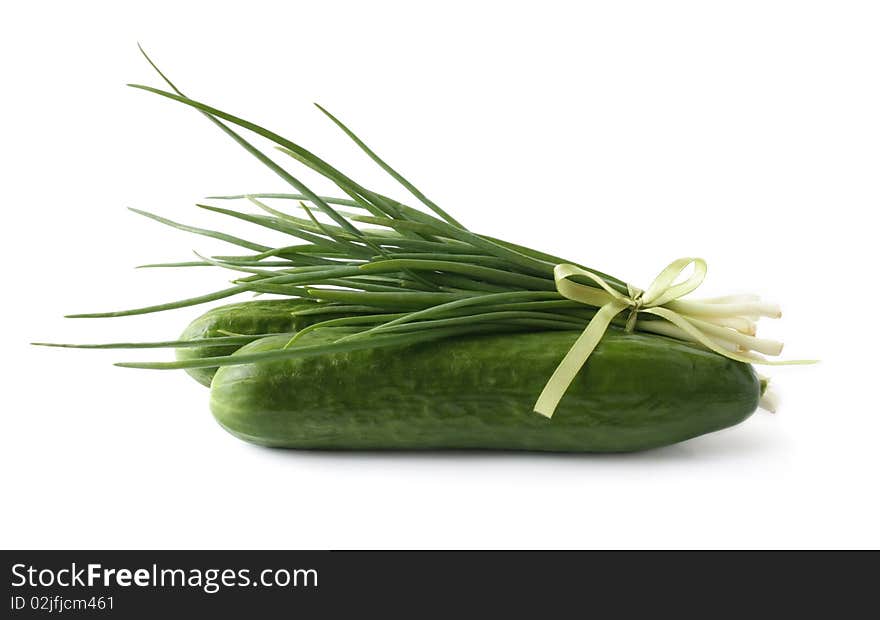 A bunch of green onions and cucumbers on a white background