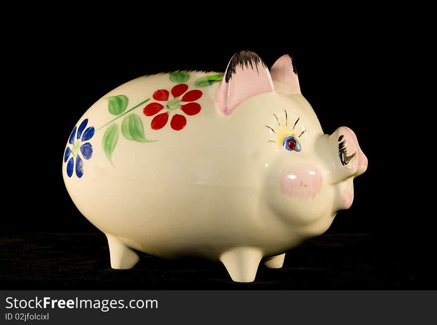 Old china piggy bank with flower pattern on a black background in portrait format