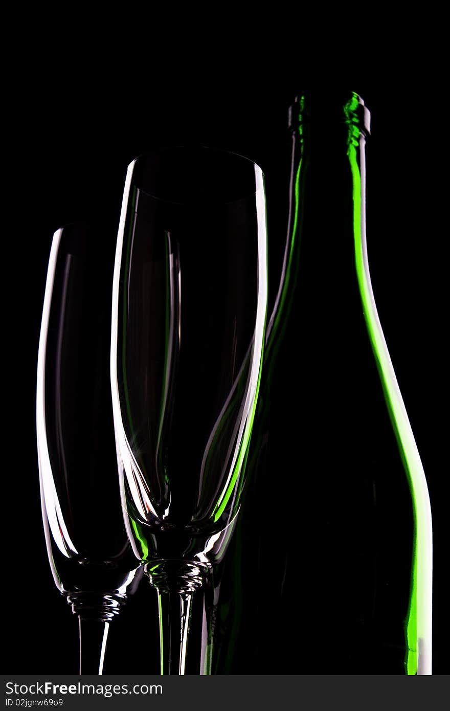 Green glass bottle of wine and wineglasses on black background