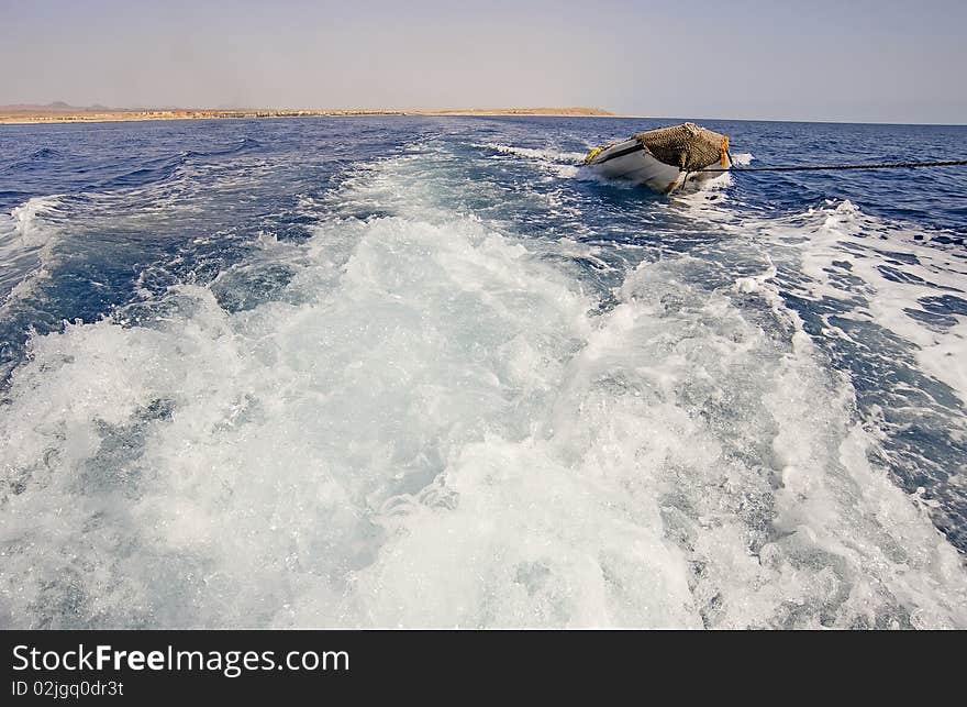 View of the wake of a motor yacht towing a small inflatable boat