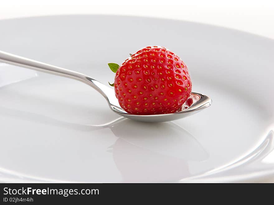 Single ripe fresh strawberry on spoon isolated on white.