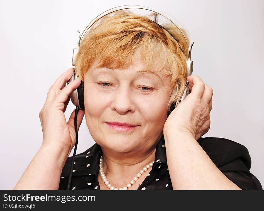 Old woman listens to music through earphones