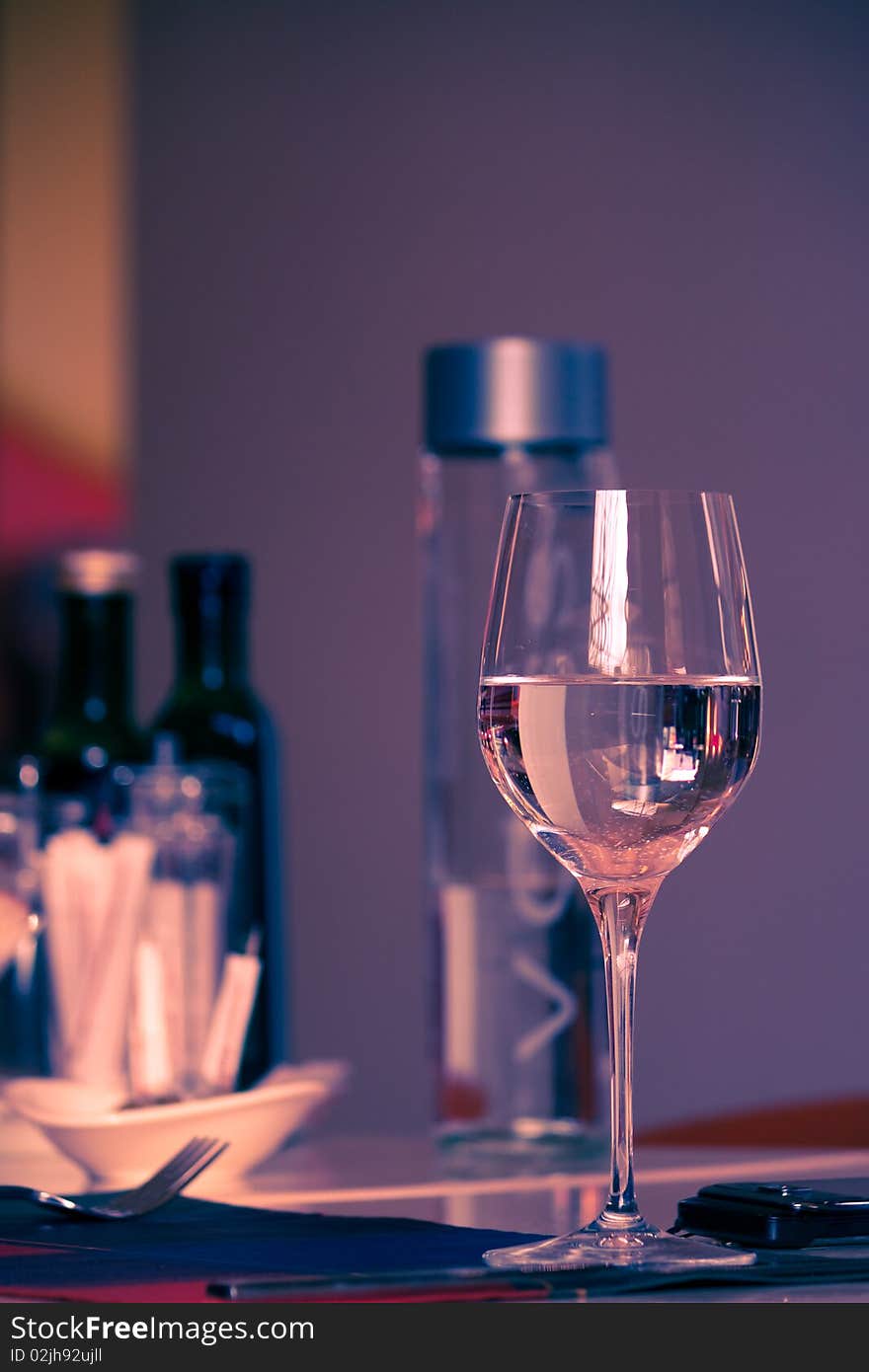 A glass full of water stands on luxury served table with modern objects. A glass full of water stands on luxury served table with modern objects