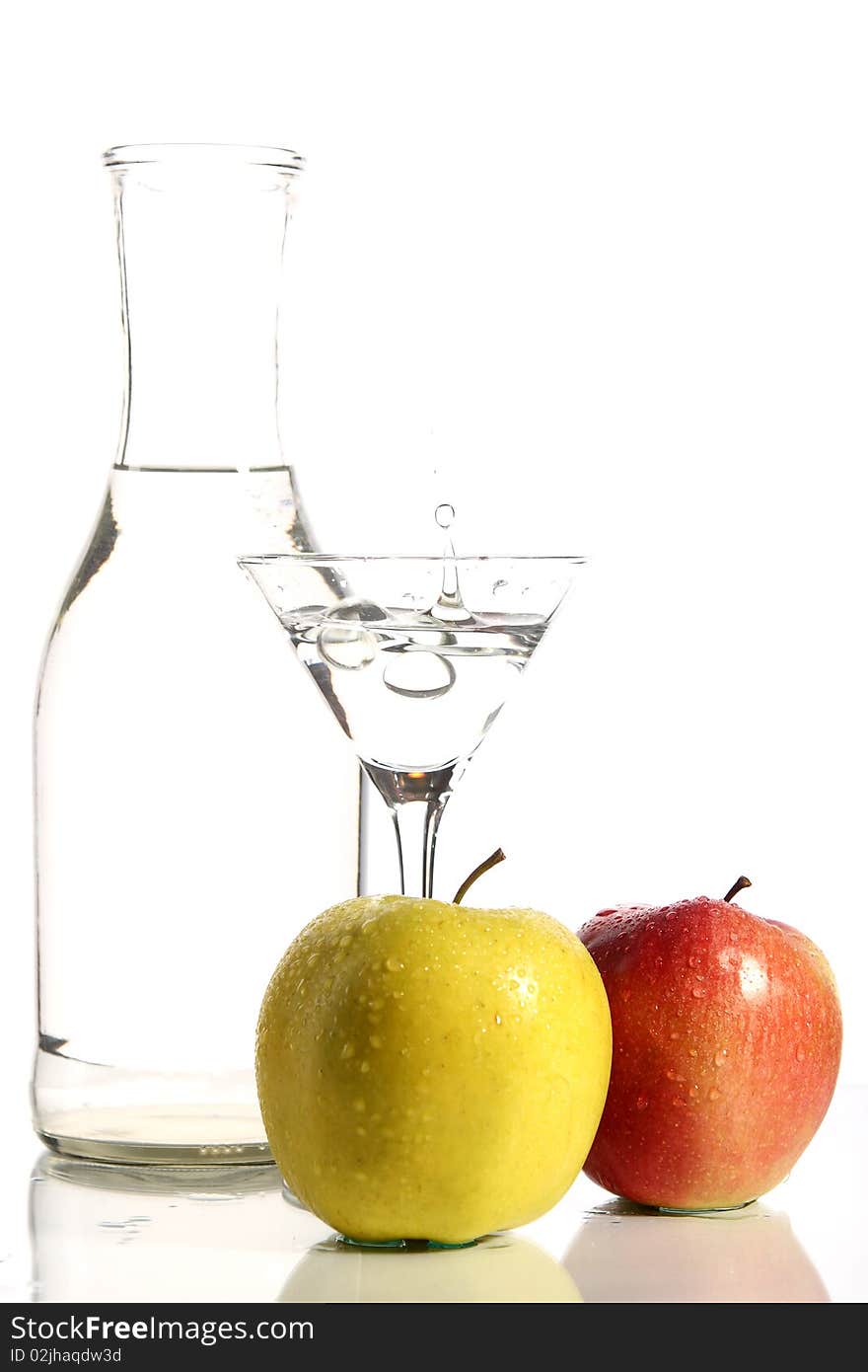 Bottle with transparent water, a glass and apples on a white background