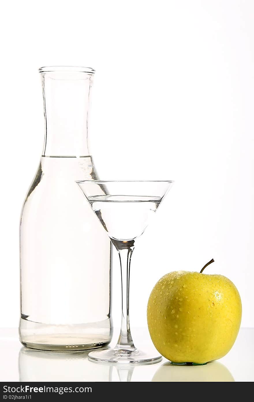 Bottle with transparent water, a glass and apples on a white background