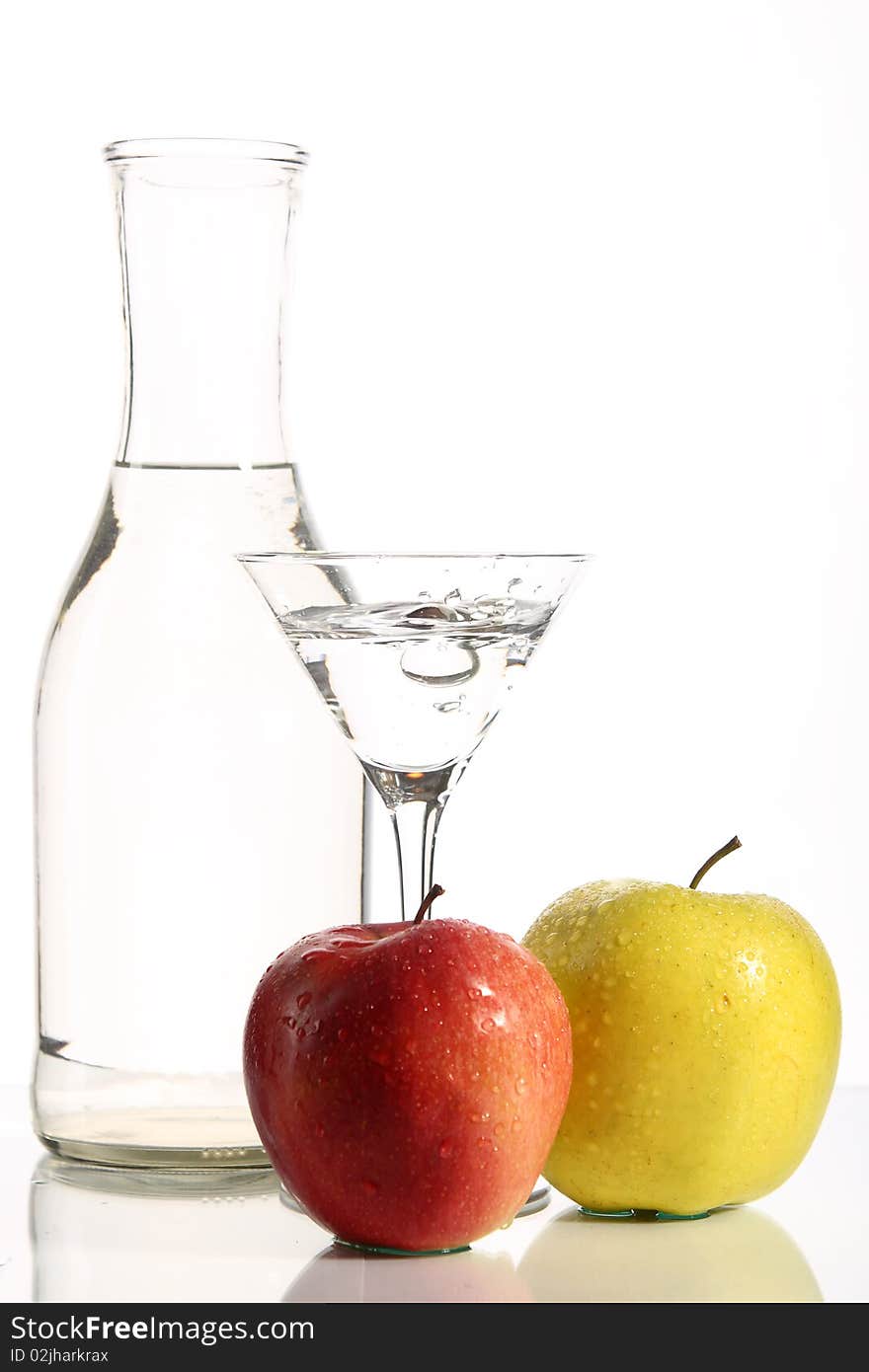 Bottle with transparent water, a glass and apples on a white background