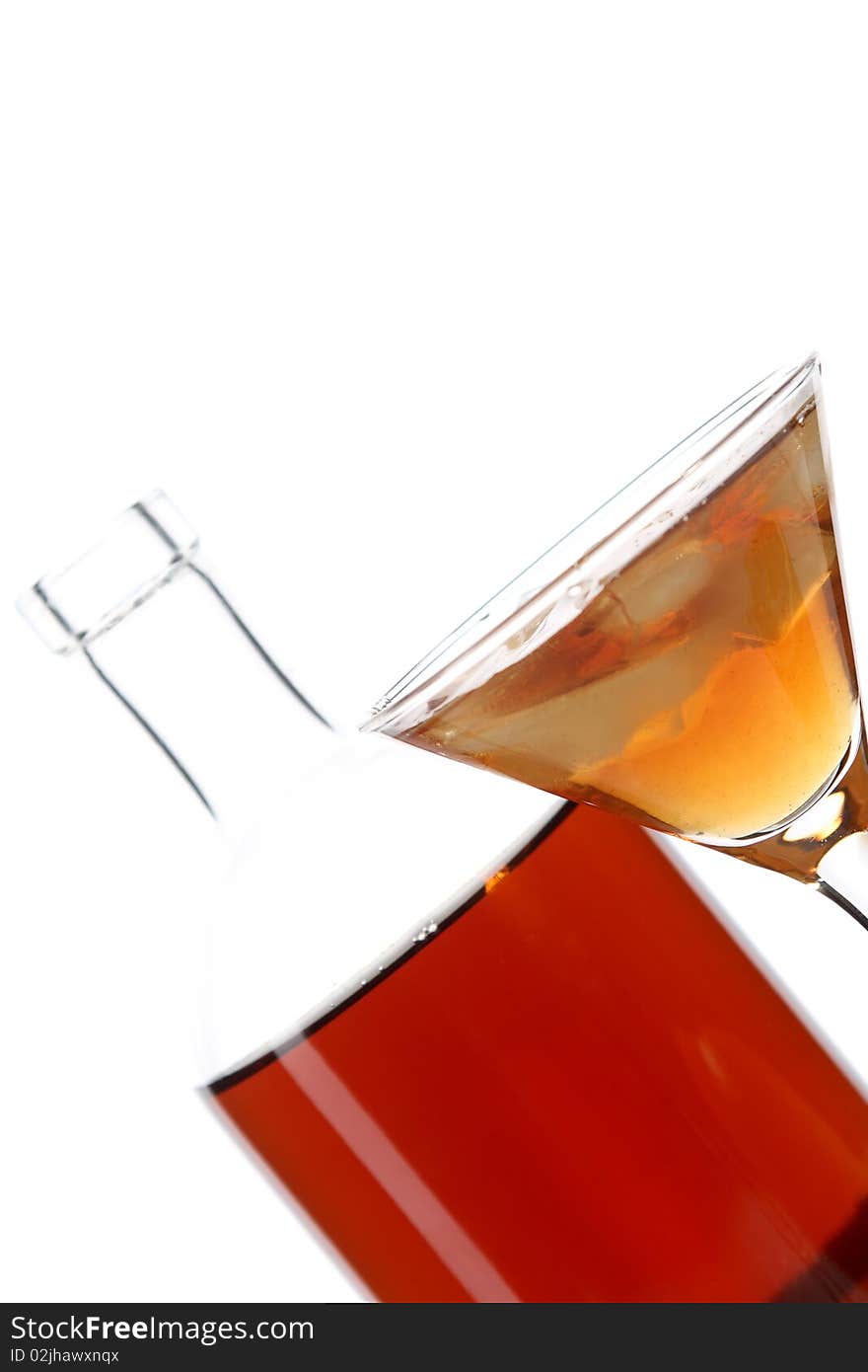 Bottle with an alcoholic drink, a glass and an orange on a white background