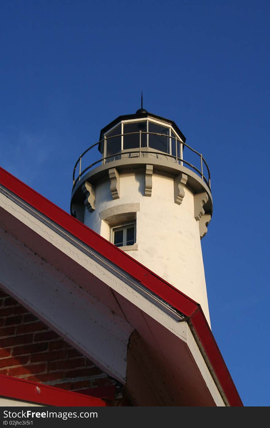 The Tawas Point Lighthouse in East Tawas, Michigan, set against a bright blue sky background.