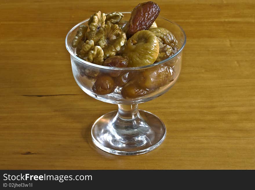 A glass dessert bowl containing figs, dates and walnuts. A glass dessert bowl containing figs, dates and walnuts