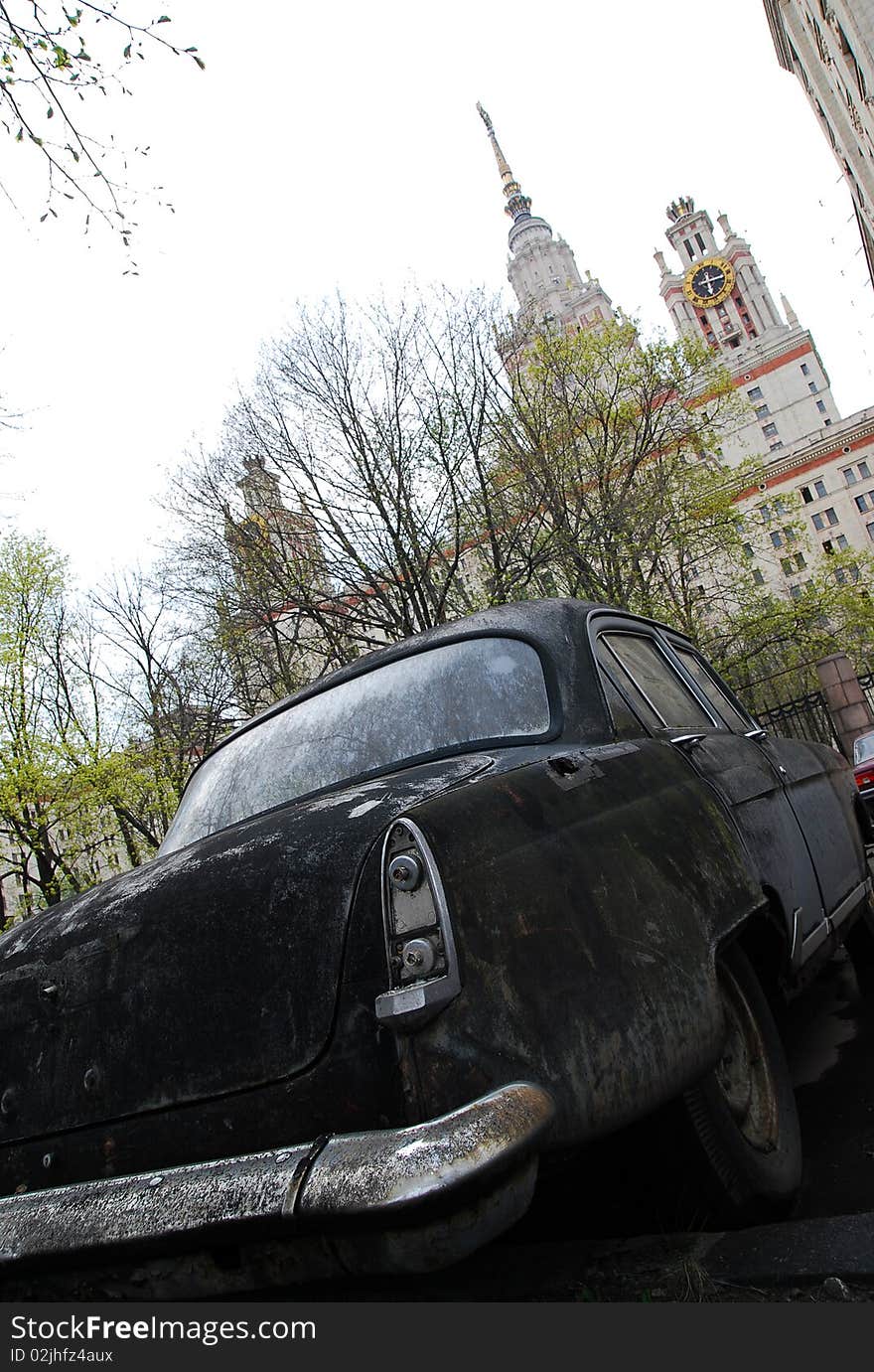 Old car on a background of trees and high-rise building