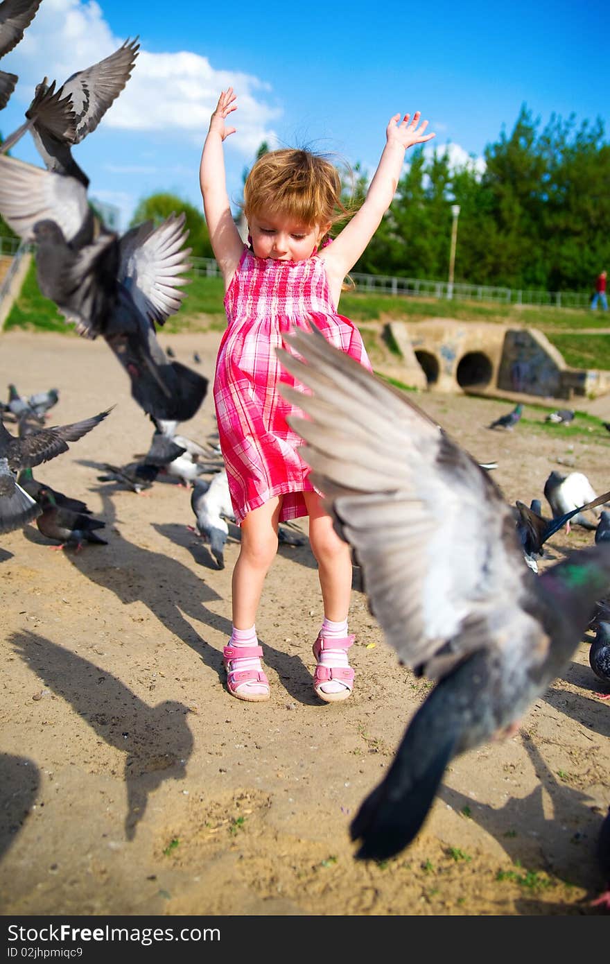 Cute little girl in pink dress feeding pigeons. Cute little girl in pink dress feeding pigeons