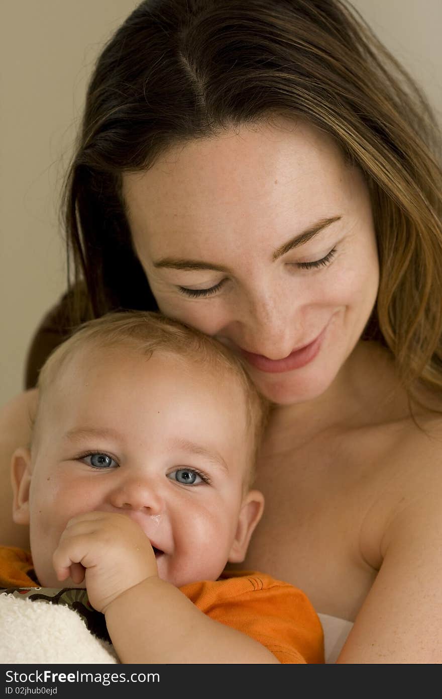 A beautiful mother and her young baby cuddling and laughing. A beautiful mother and her young baby cuddling and laughing.