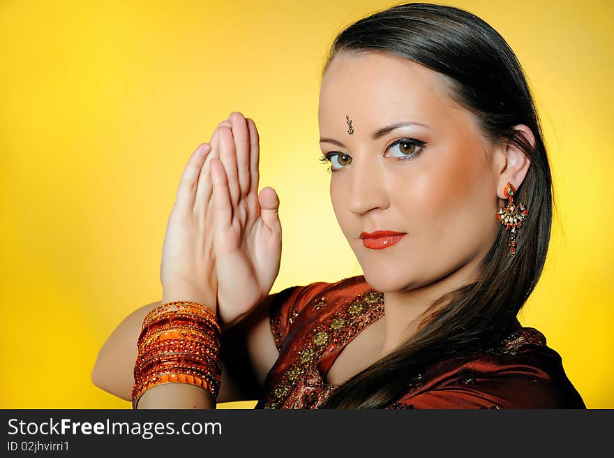 Young beautiful woman in indian traditional jewellery, bindi and make-up. yellow background. Young beautiful woman in indian traditional jewellery, bindi and make-up. yellow background