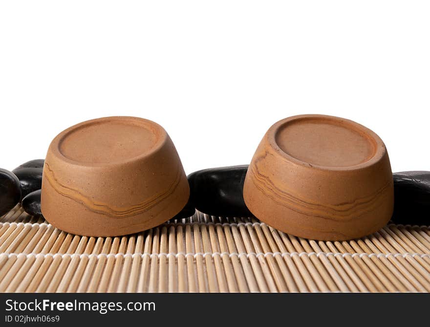 Two turned clay cups, mat and stones