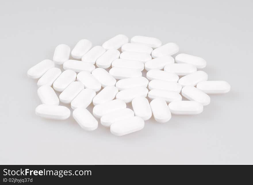 White pills lying on a light background. Close-up.