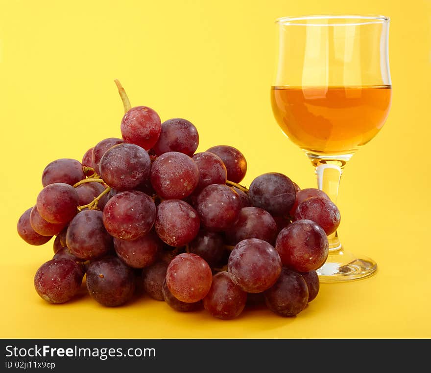 Branch of grape with wineglass on yellow background