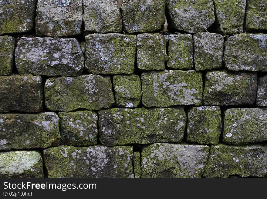 An old dry stone wall with green moss and lichen. An old dry stone wall with green moss and lichen