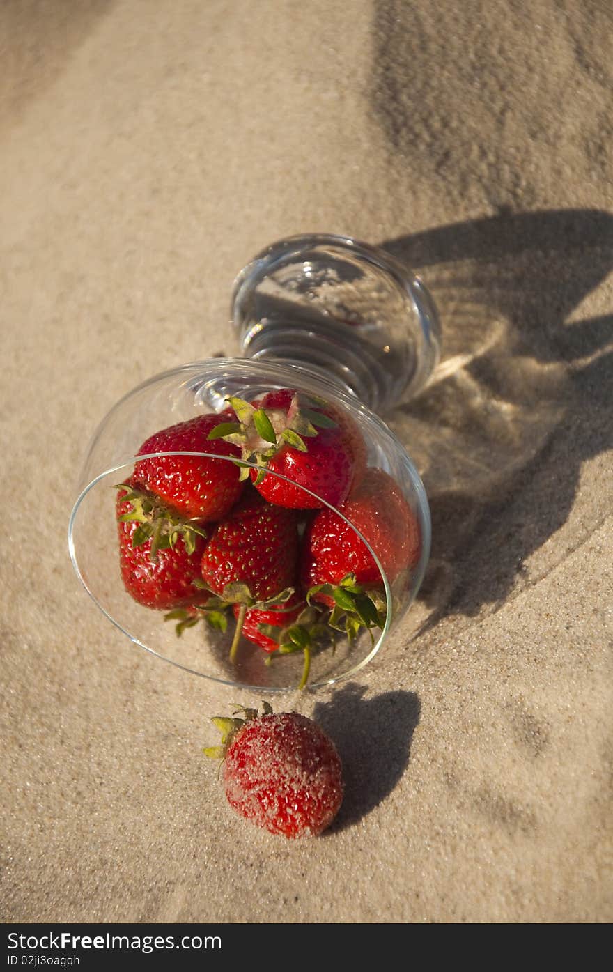 Ripe red strawberries in a glass on the sand. Ripe red strawberries in a glass on the sand