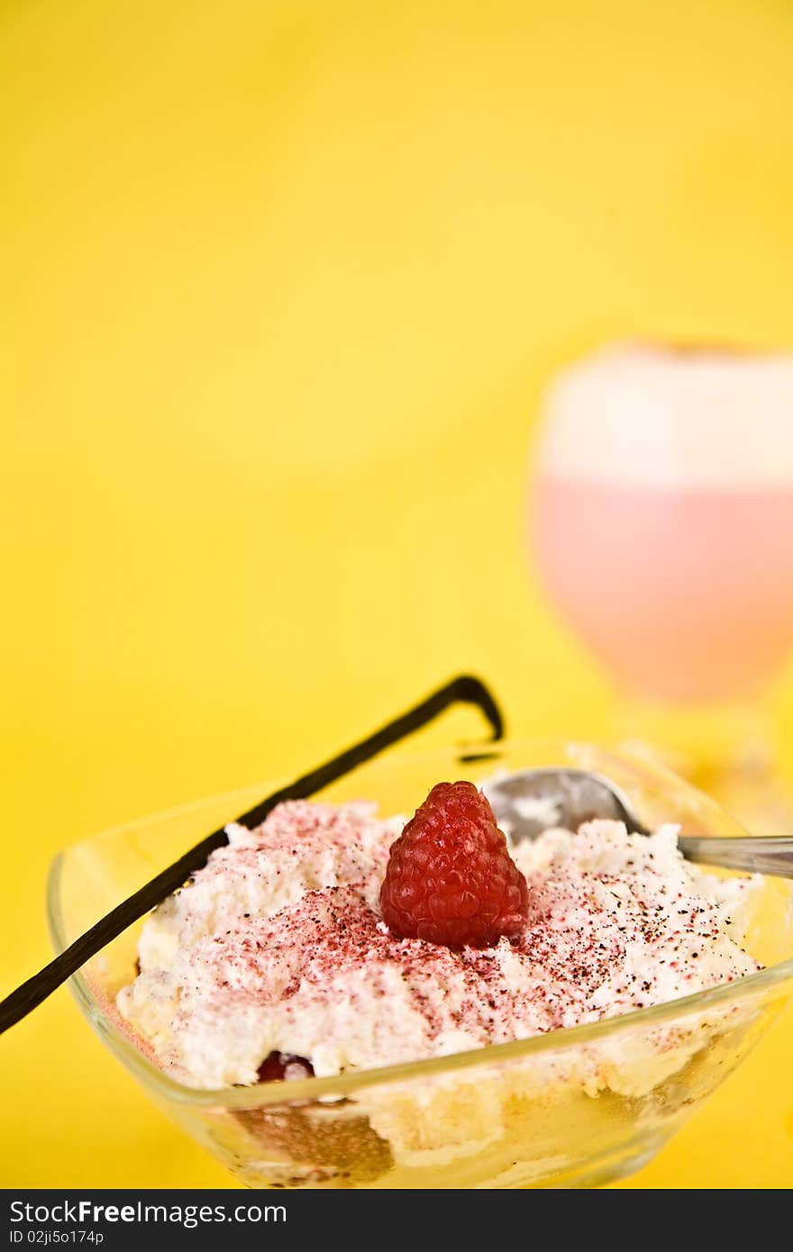 Whipped cream with strawberry and sprinkles in glass dish against yellow background. Whipped cream with strawberry and sprinkles in glass dish against yellow background