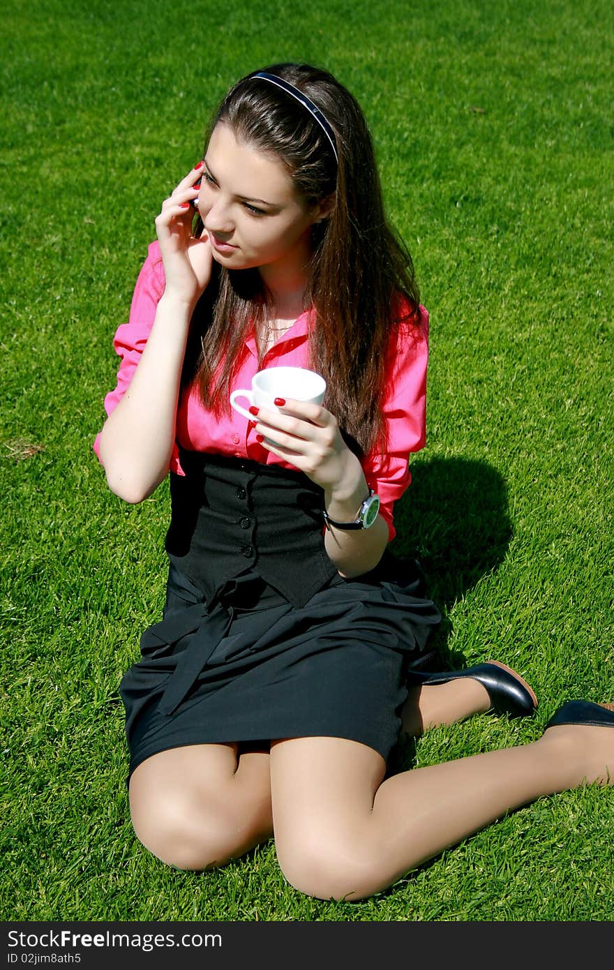 Young businesswoman drinking tea and talking at the green field