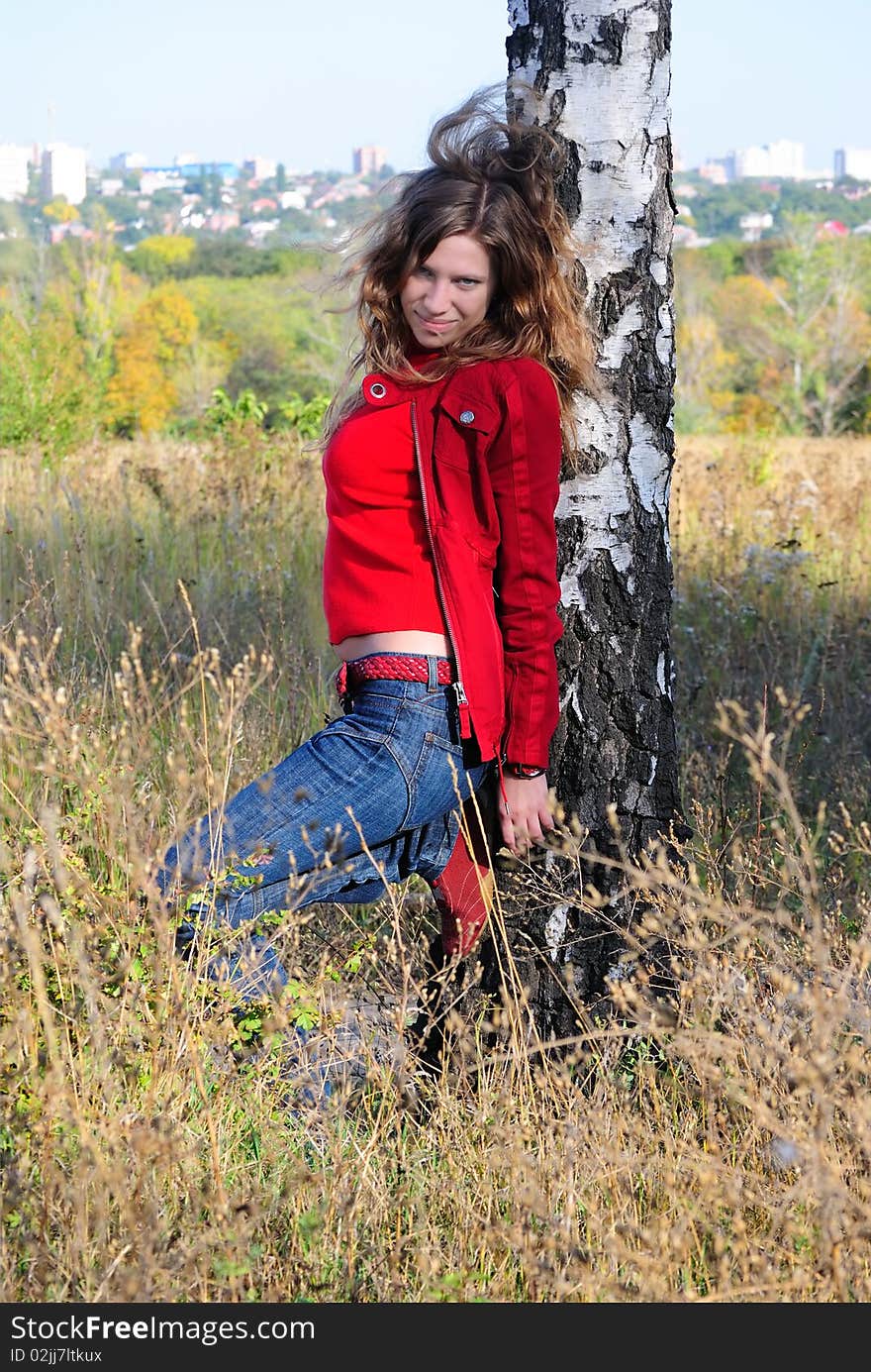 The girl leans against a birch and looks forward. The girl leans against a birch and looks forward