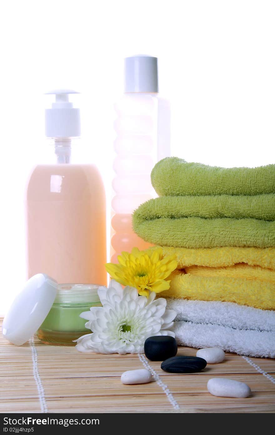 Bath products with flowers and towels on bamboo mat. Bath products with flowers and towels on bamboo mat