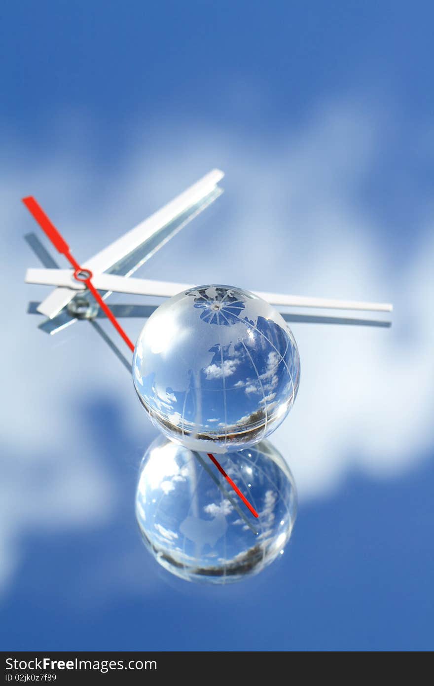 Glass glode and clock hands lying on mirror background with blue sky reverberation. Glass glode and clock hands lying on mirror background with blue sky reverberation