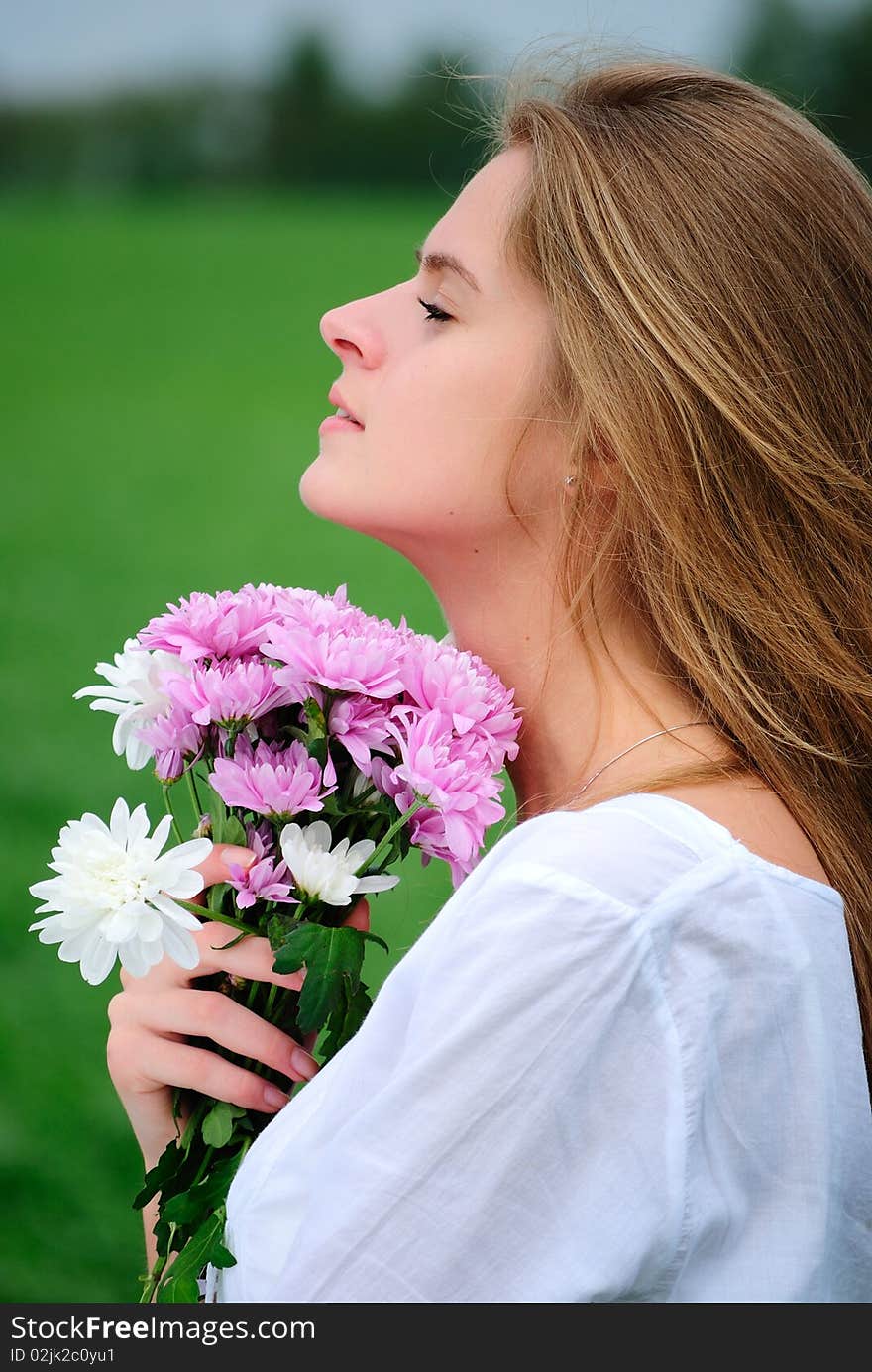 The beautiful girl with a bunch of flowers in the field. The beautiful girl with a bunch of flowers in the field