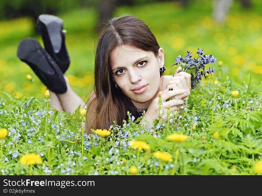 Girl lying in a grass with a bunch of flowers