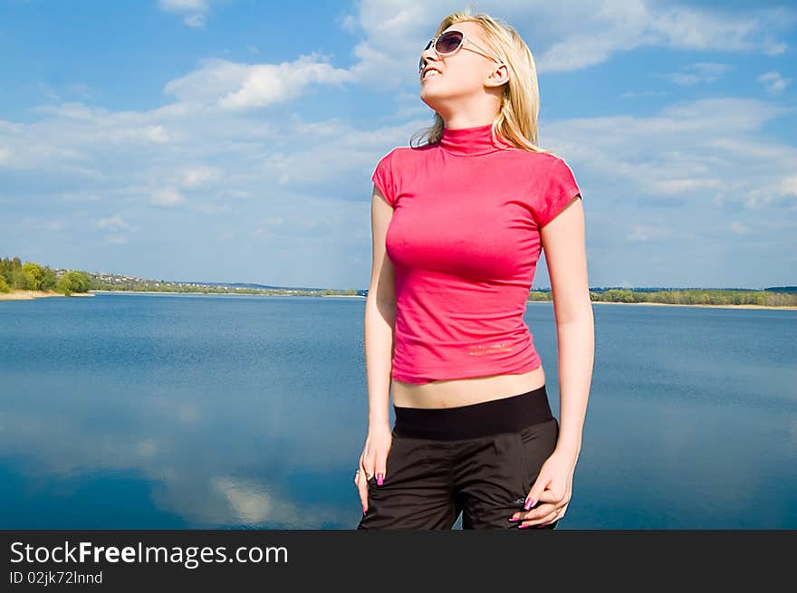 The blonde in a pink jacket against the nature looking sideways. The blonde in a pink jacket against the nature looking sideways