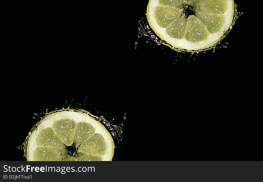 Lemon slice in water splashes on a black background