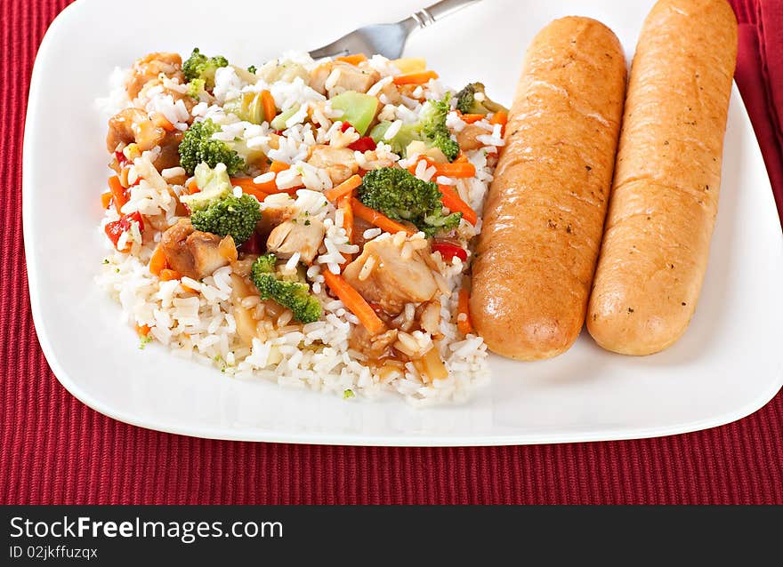 Chicken teriyaki over rice with bread sticks on a plate