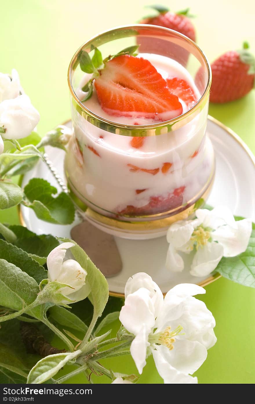 Strawberry yogurt with fresh strawberry in glass. On a 
green background