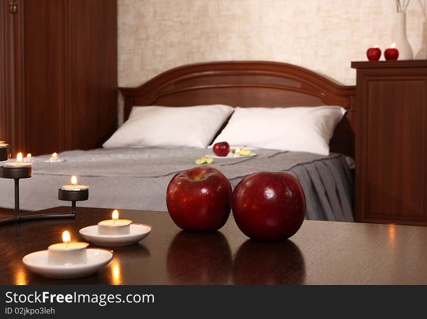 Little table in a bedroom , decorated with burning candles and apples