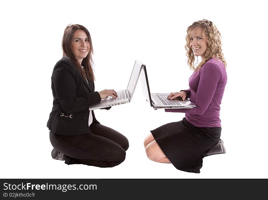 Two women have laptop computers back to back and are smiling. Two women have laptop computers back to back and are smiling.