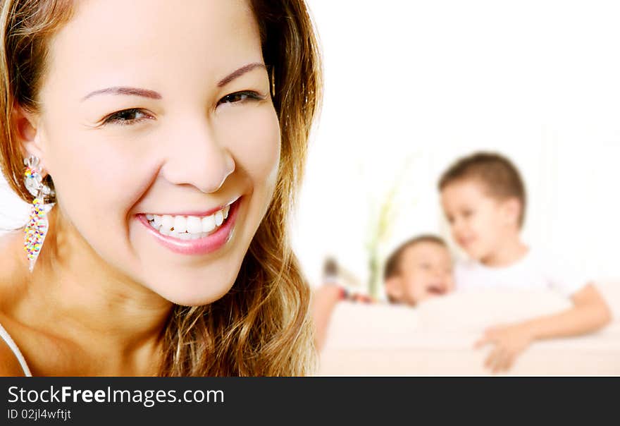 Young mother smiling and looking at the camera, In the background the children playing. Young mother smiling and looking at the camera, In the background the children playing