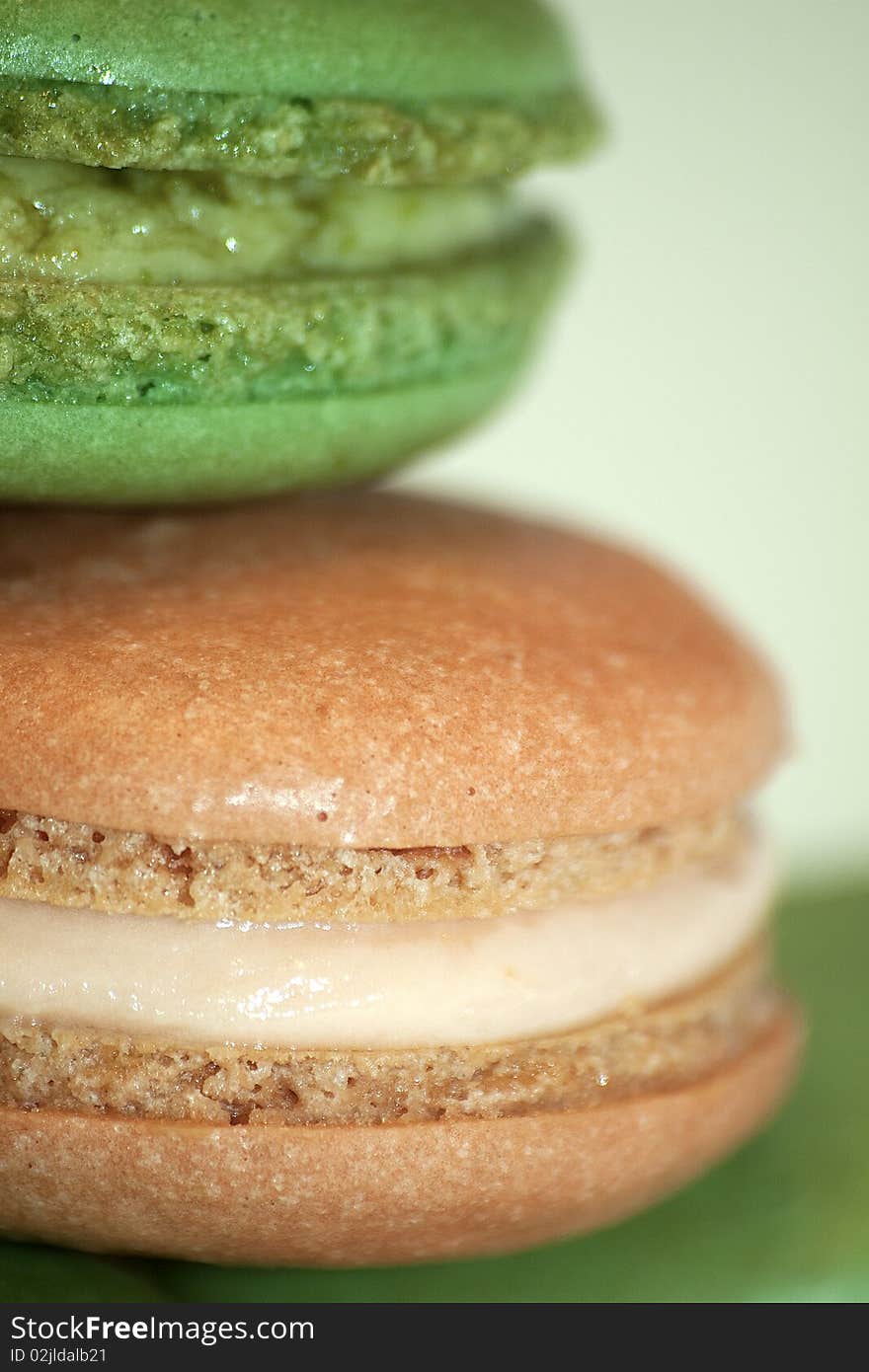 Pistachio and lemon French macaron close up on a green background. Pistachio and lemon French macaron close up on a green background