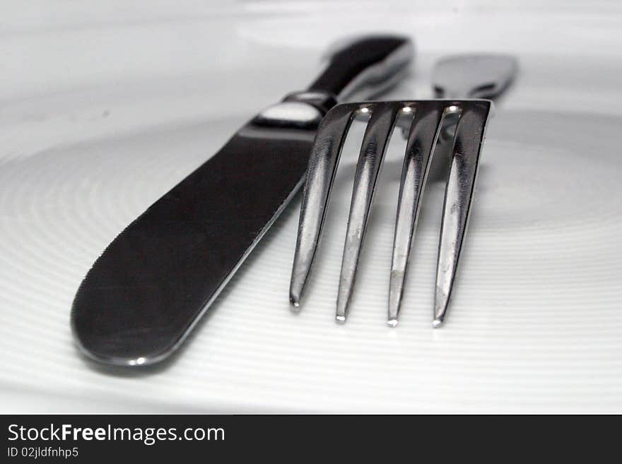 A fork and a knife on white dish. A fork and a knife on white dish