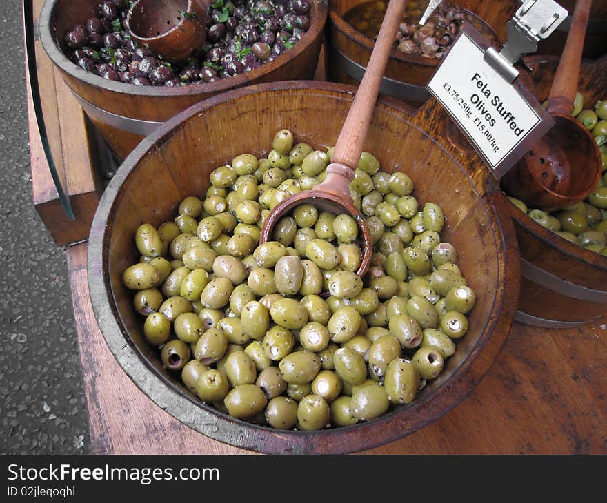 Green olives on a wooden pot background